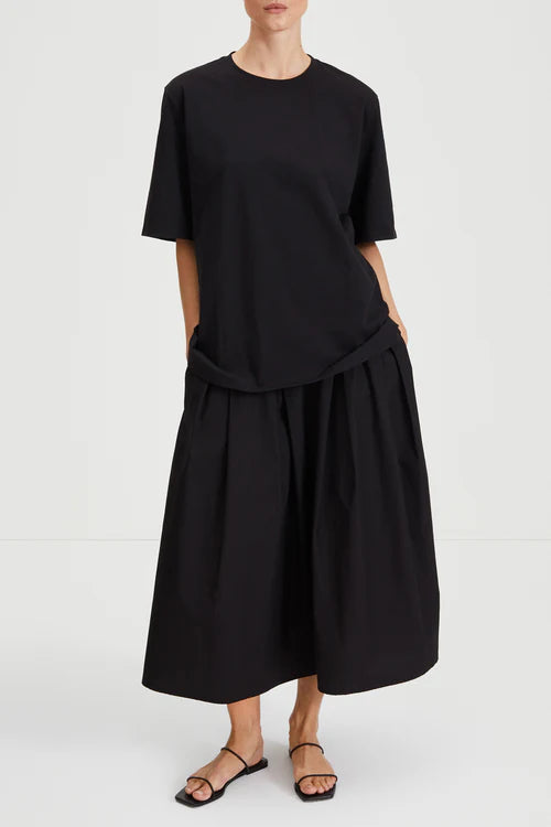 Person wearing a black outfit with a top and skirt on a white background