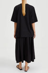 Person wearing a black outfit with a plain background