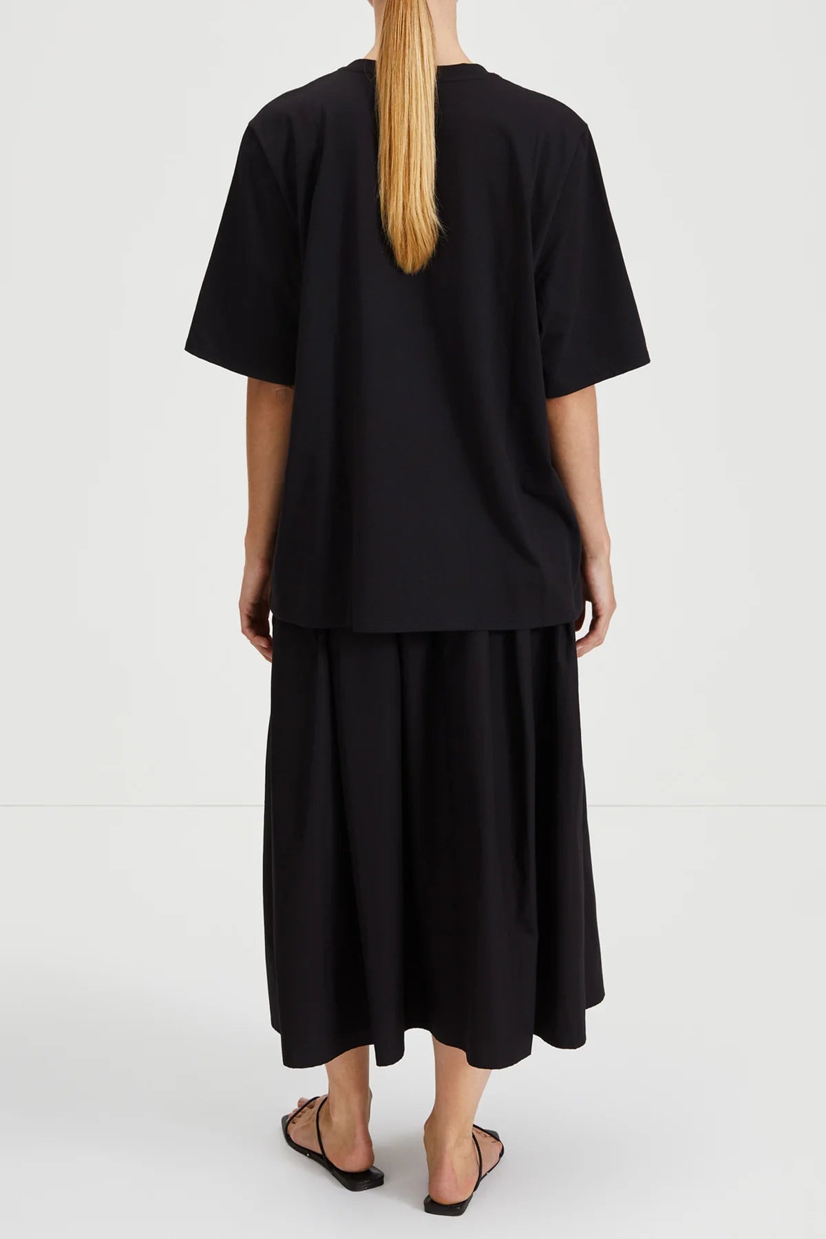 Person wearing a black outfit with a plain background