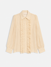 A pale cream or light beige long-sleeve blouse with a pointed collar, gathered sleeves, and a central vertical ruffle detail, shown on a plain light background.