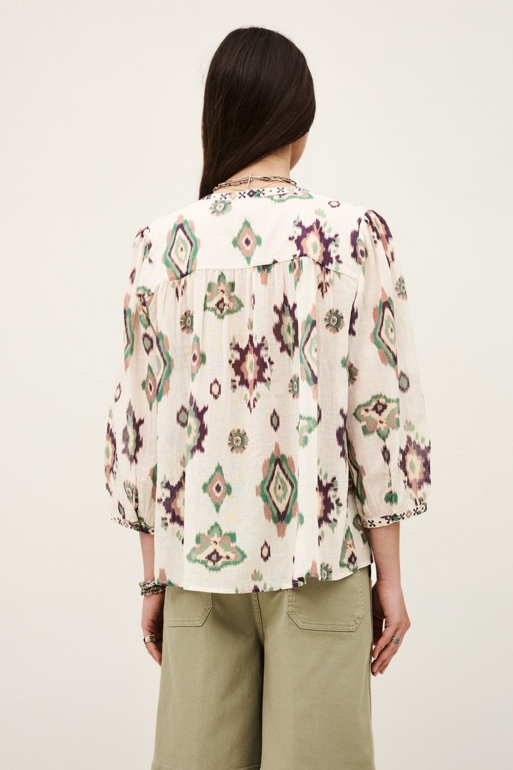 Person wearing a patterned blouse with a plain background rear view from ba&sh