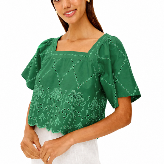 Woman wearing a green blouse with white pants on a white background