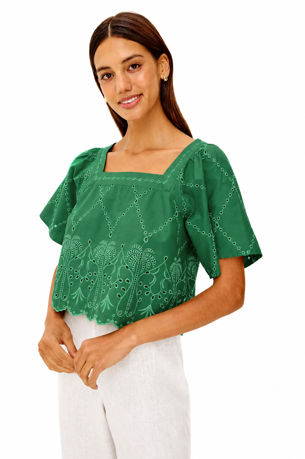 Woman wearing a green blouse with white pants on a white background