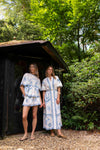 Two women in matching patterned outfits standing in a garden setting.