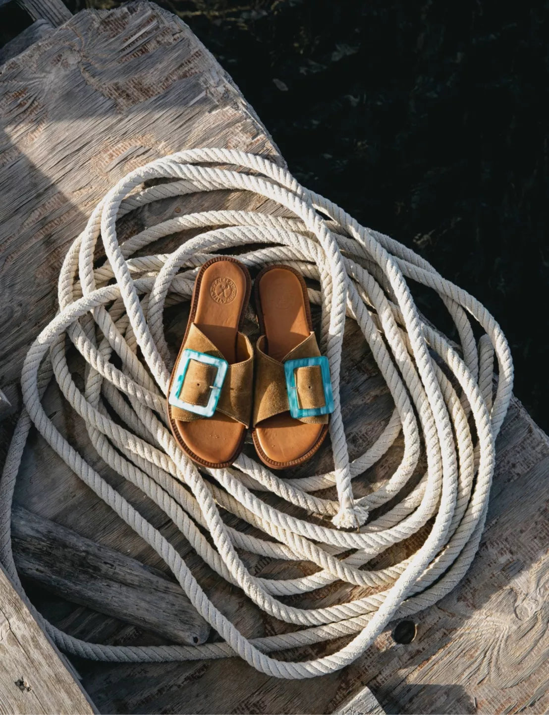 Brown sandals with turquoise buckles on a coiled rope