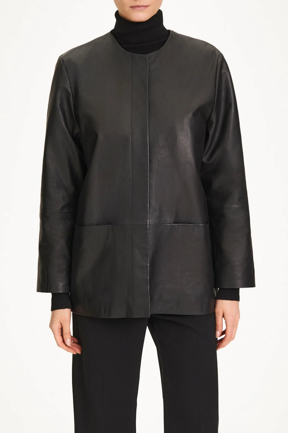 A model wearing a black leather jacket with a high mock neck, long sleeves, and front patch pockets, paired with black trousers.