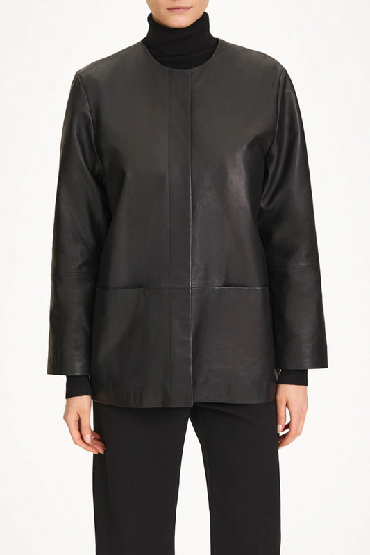 A model wearing a black leather jacket with a high mock neck, long sleeves, and front patch pockets, paired with black trousers.