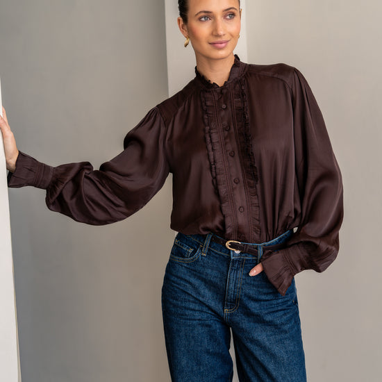 Woman wearing brown shirt and jeans posing close up