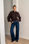 Woman wearing a brown blouse and jeans looking into the camera
