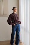 woman wearing brown blouse with blue jeans looking out of window
