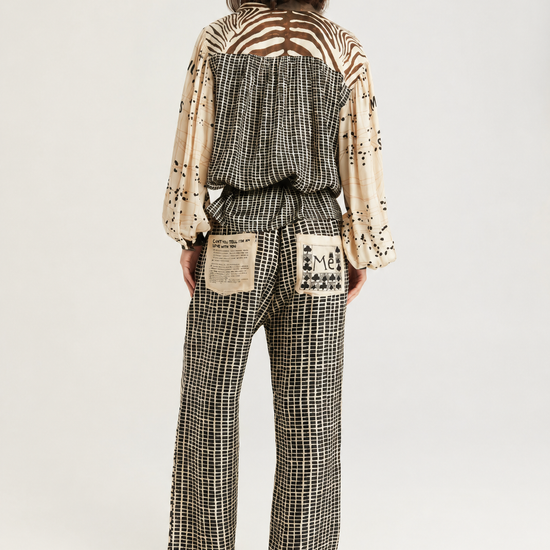 A model wearing a matching zebra-print jumpsuit with a brown belt, photographed against a plain light gray studio background.