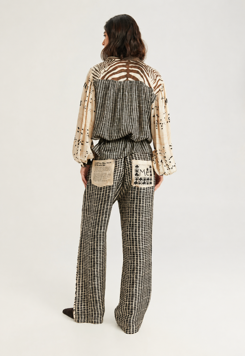 A model wearing a matching zebra-print jumpsuit with a brown belt, photographed against a plain light gray studio background.