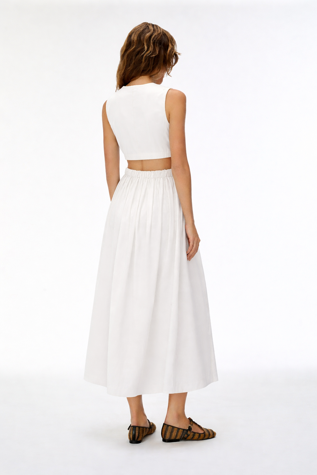 Woman wearing a white sleeveless top and long skirt on a white background