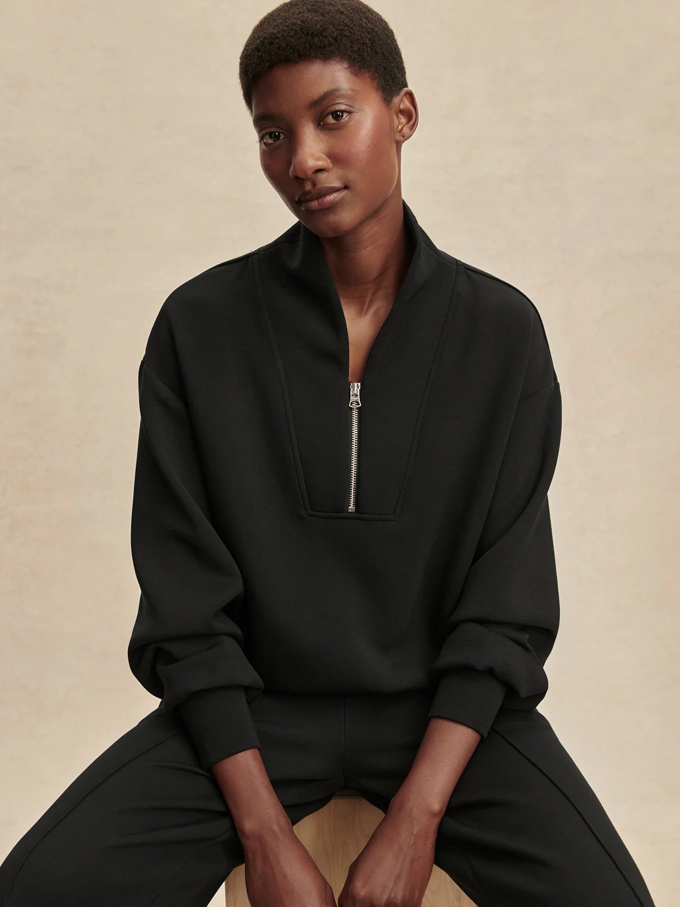 Quarter zip and slightly cropped black sweat top with shawl collar and V neckline from varley model shot