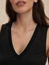 Close-up of a woman wearing a black sleeveless top with a deep neckline.