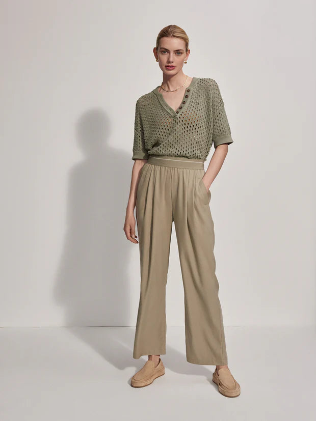 Model wearing stone colour loose fitting trousers with sage green top.