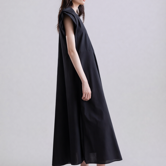 Woman wearing a black sleeveless dress on a plain background