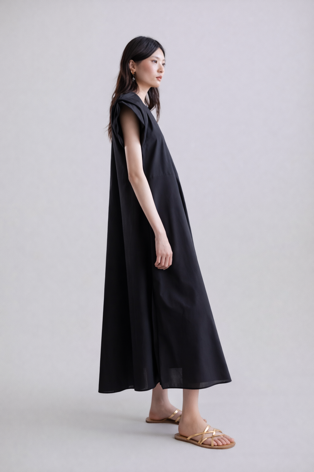 Woman wearing a black sleeveless dress on a plain background