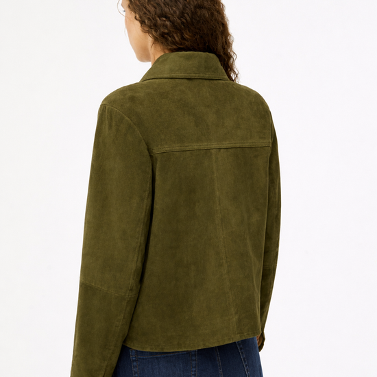 Person wearing a green jacket and blue jeans on a white background