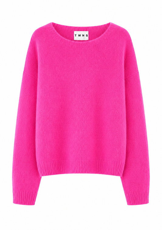 A bright pink crewneck sweater with long sleeves and ribbed cuffs and hem, shown against a plain white background. The inside collar label shows the brand name 'TWNS'.