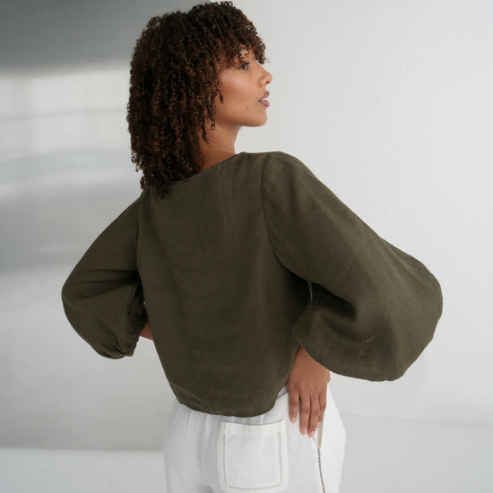 Woman wearing a green blouse with puffed sleeves against a white background