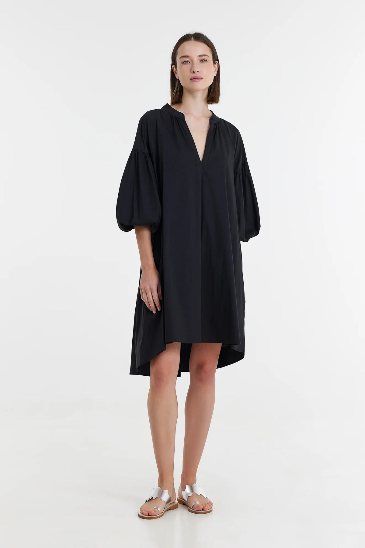 Black knee length trapeze dress with notch neck and three quarter length sleeves with elasticated cuffs