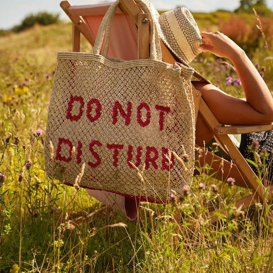 straw bag with slogan hanging on a deck chair 