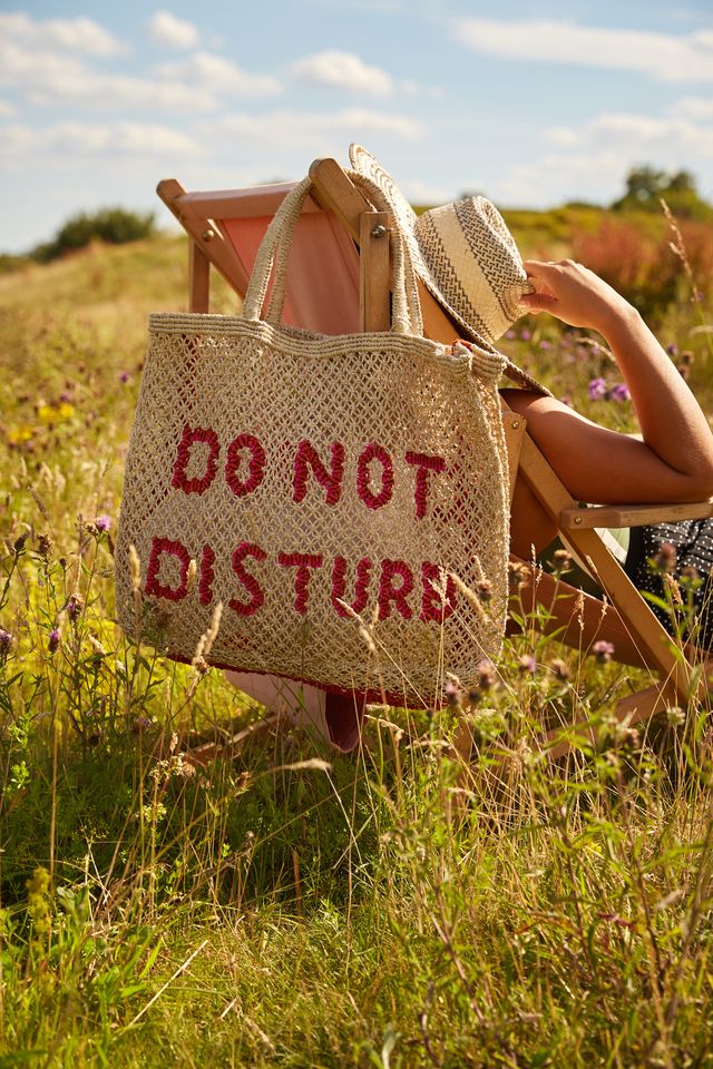 straw bag with slogan hanging on a deck chair 