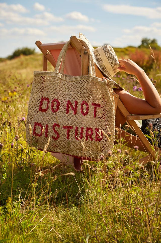 straw bag with slogan hanging on a deck chair 