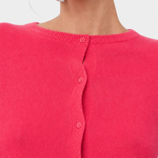 Close-up of a model wearing a bright pink ribbed knit cardigan sweater with a button-up front.