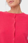 Close-up of a model wearing a bright pink ribbed knit cardigan sweater with a button-up front.