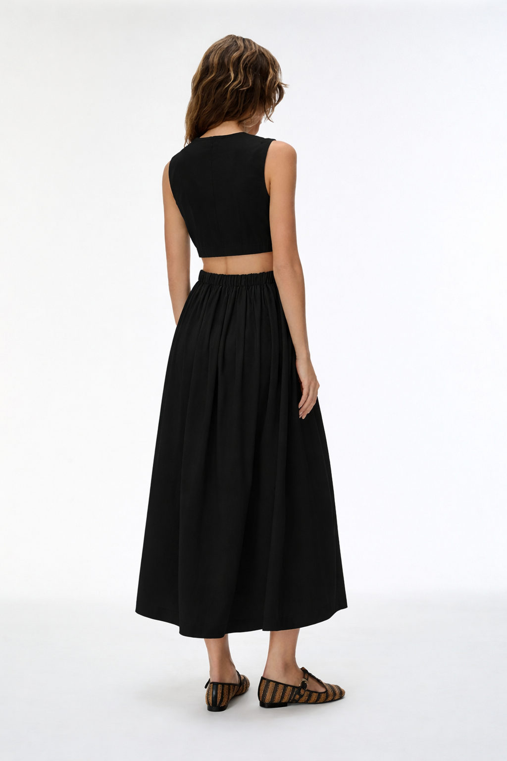 Woman wearing a black sleeveless top and long skirt on a white background