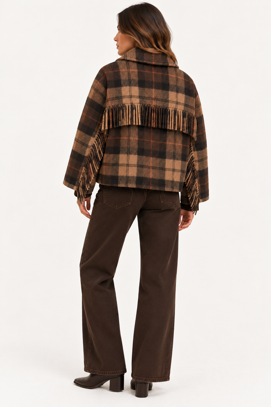 A woman shown from the back wearing a brown and tan plaid fringed cape jacket with dark brown wide-leg pants and black boots, against a plain white studio background.