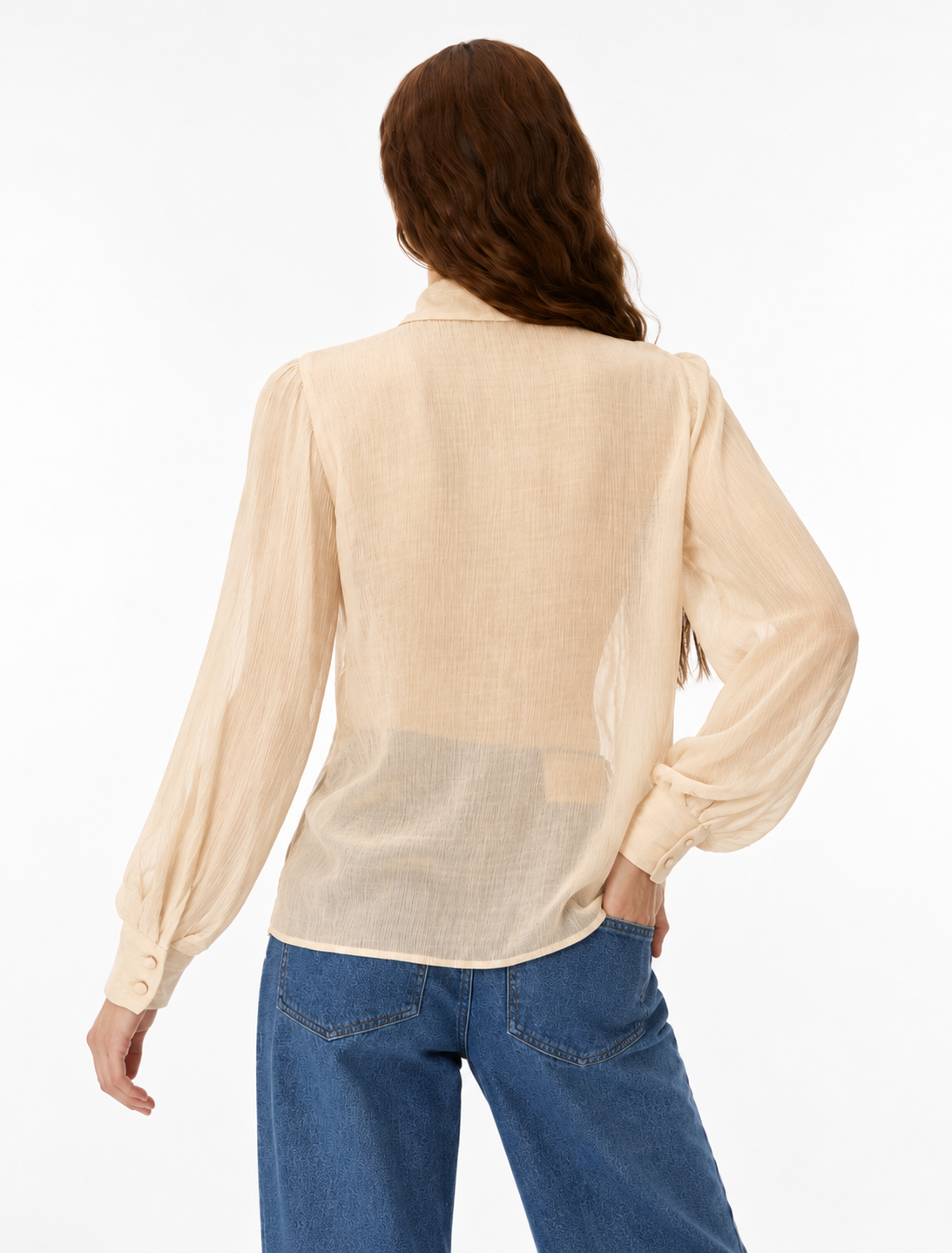 A woman shown from the back wearing a light beige long-sleeve blouse and blue jeans against a plain white studio background.