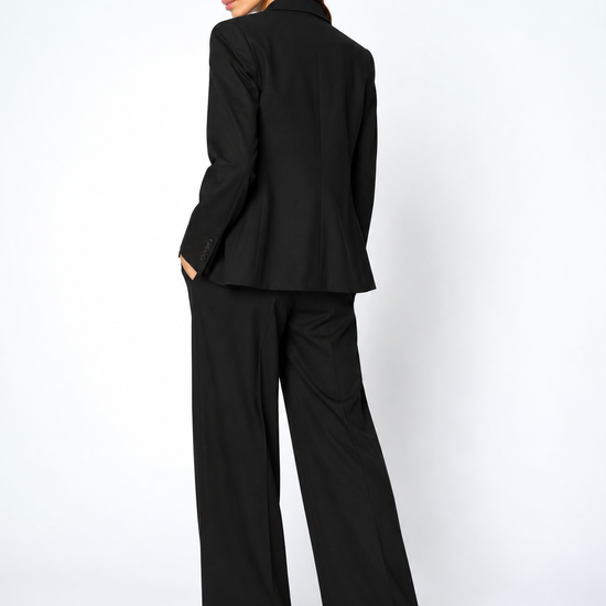 model wearing a black suit facing away from the camera 