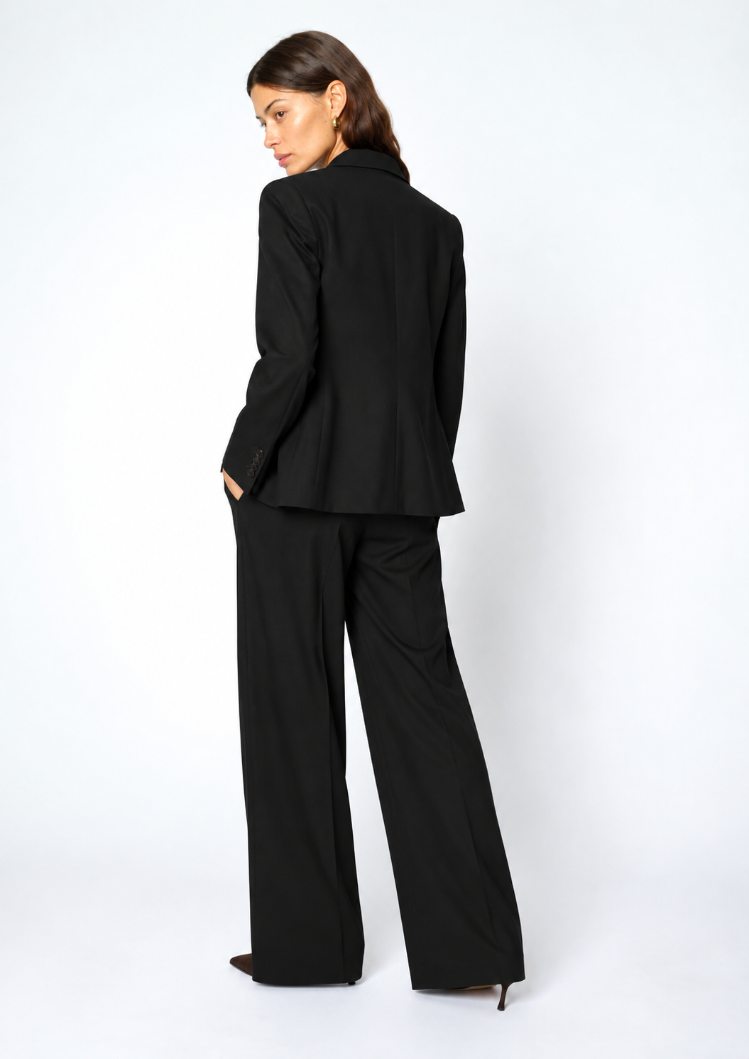 model wearing a black suit facing away from the camera 