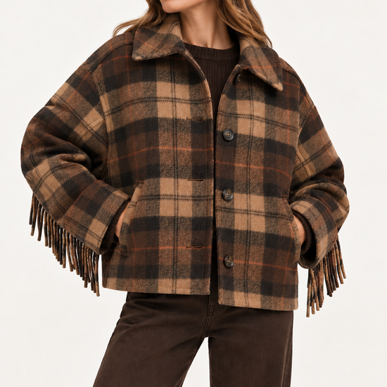 A woman wearing a brown and tan plaid fringed jacket with a collar, paired with dark brown pants, photographed against a clean white studio background.