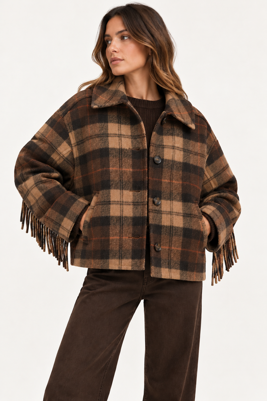 A woman wearing a brown and tan plaid fringed jacket with a collar, paired with dark brown pants, photographed against a clean white studio background.