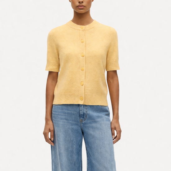 model wearing yellow jumper and jeans on plain background