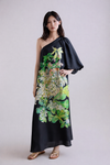 Woman wearing a black one-shoulder dress with floral print on a plain background