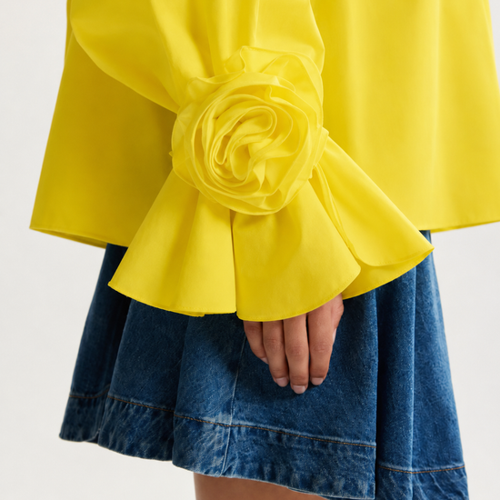 Yellow blouse with ruffled sleeves and a blue denim skirt on a white background