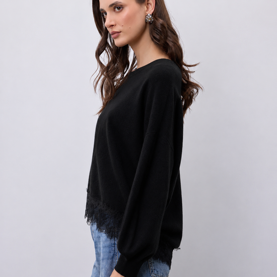 model wearing a black crew neckline knit with lace hem and blue jeans 
