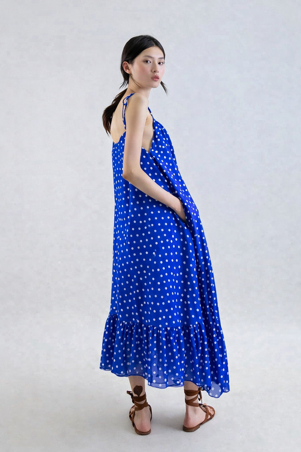 Woman wearing a blue polka dot dress on a white background