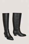 A pair of black leather knee-high boots with low block heels and pointed toes, displayed against a solid light gray background.