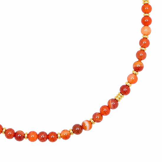 A beaded necklace featuring round orange and red agate beads separated by small gold spacer beads, shown against a plain white background.