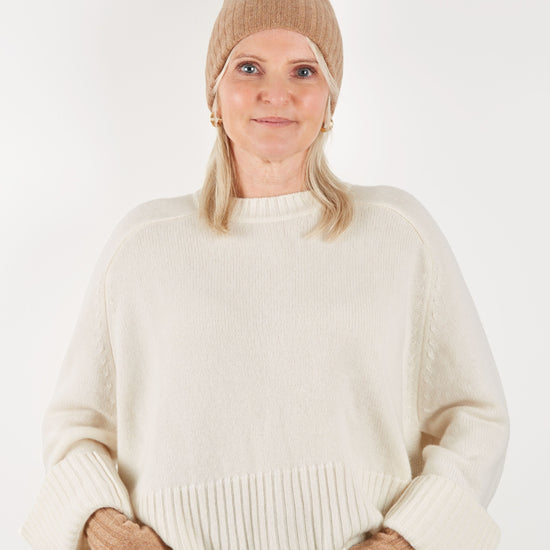 Camel coloured beanie hat and wrist warmer set on model with cream knit