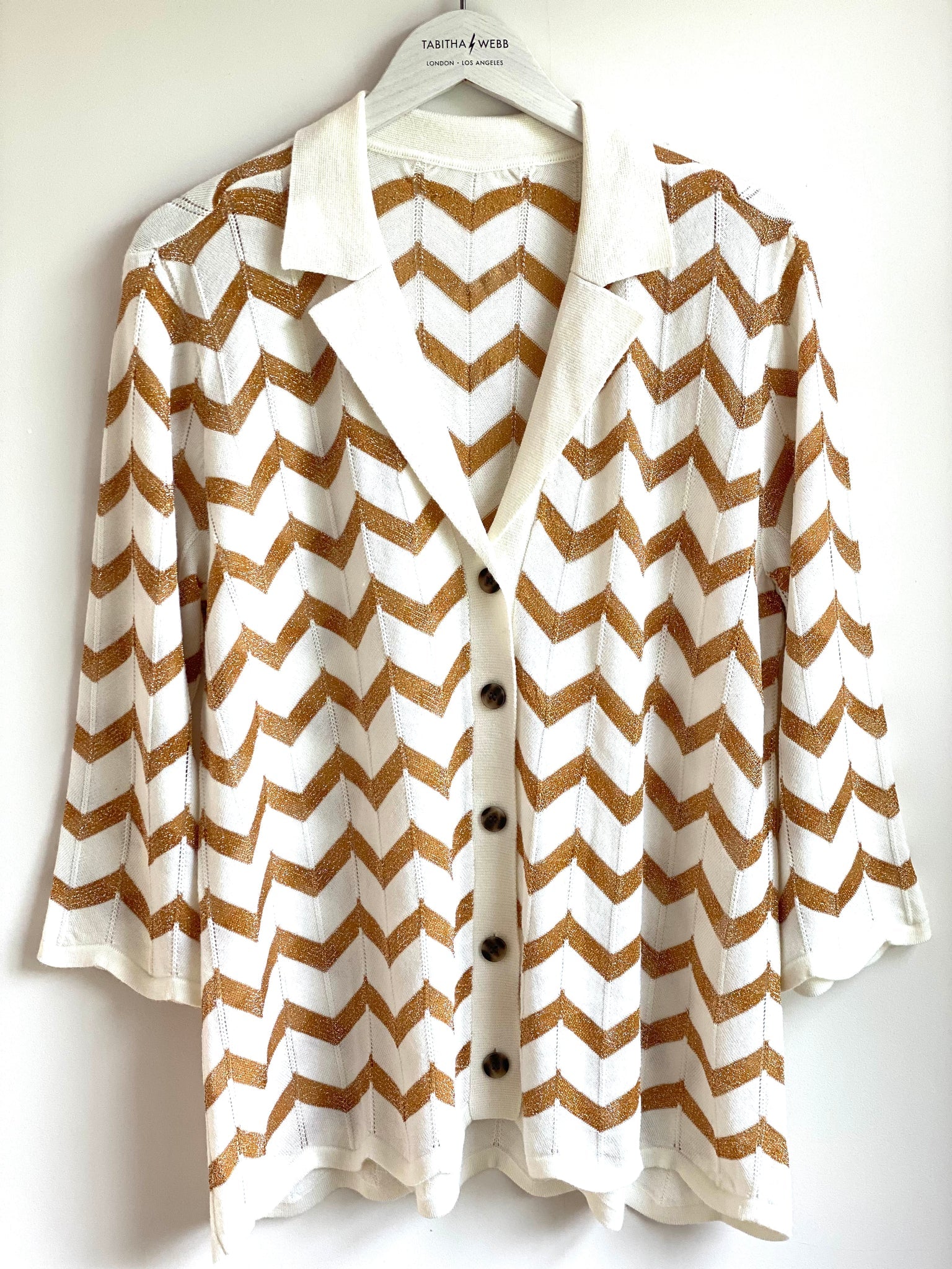 White and gold chevron top with classic collar and notch lapel with three quarter length sleeves and zig-zag hem and cuffs