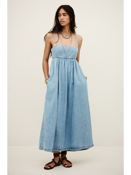 Woman wearing a light blue denim dress on a white background