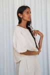 Woman wearing a white outfit against a light gray curtain background from Lilly Pilly