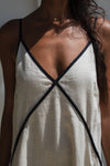 top of beige linen dress with black straps worn by a person against a neutral background